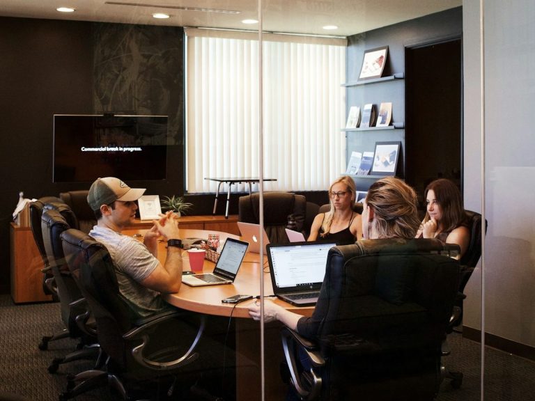 A group of four people having a meeting around a conference table.
