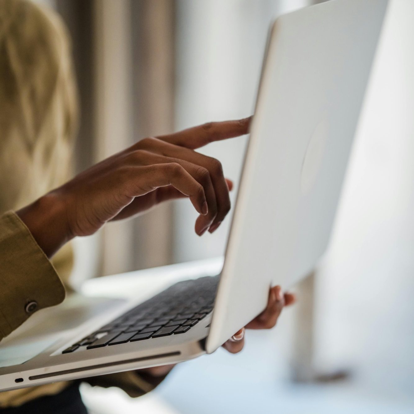 A hand using a laptop, with a soft-focus background.