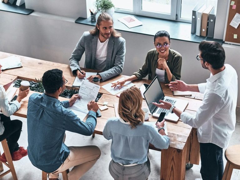 A diverse group of people engaged in a collaborative meeting around a table.